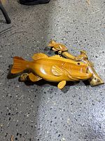 Oblique view showing large and small carved fish on driftwood base