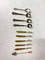 All 11 pieces laid out showing spoons, wood-handled forks, and decorative fork
