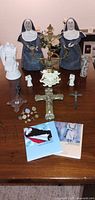 Full lot overview on table showing crucifixes, candelabra, figurines, pins, booklets