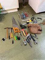 Overall view of mixed tools spread on floor with belt visible