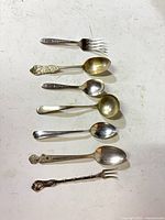 Seven assorted flatware pieces laid vertically for identification