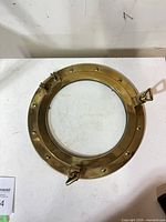 Front view of brass porthole with glass pane and latches