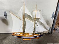 starboard side of schooner model on stand showing sails, hull paint, anchor