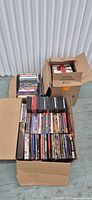 Two open cardboard boxes and one partially closed box filled with DVD cases