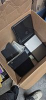 Box containing multiple black Dell and silver HP laptops
