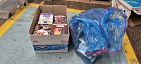 Box of DVDs and blue bag with more DVDs