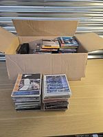 Open cardboard box filled with audio CDs plus two exterior stacks