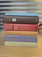 Stack of six hardcover books showing spines with titles and authors