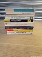 Stack of eight paperback books showing spines and titles