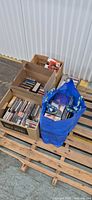Two boxes and blue tote filled with CDs on pallet