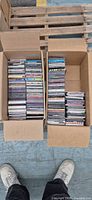 Two cardboard boxes filled with stacked CDs