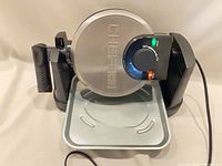 Front view showing Chefman waffle maker on base with drip tray and indicator lights