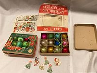 Overview of two Shiny Brite ornament boxes, Gift Dressings envelope, gift seal sheet and loose seals