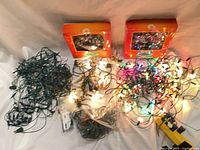 Overall lot with two boxed treetops, several tangled light strings, replacement bulbs and adapter