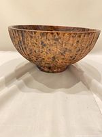 Side profile of round mango wood bowl displaying exterior grain and footed base