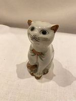 front view of ceramic cat showing facial details and tail