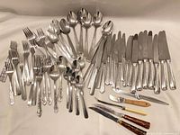 Overview of entire assortment of silver-plated flatware and steak knives.