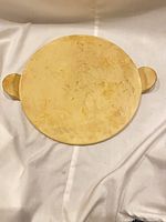 Top view of round beige pizza stone with side handles