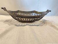 Side profile of pierced silver-plated basket showing handles and depth