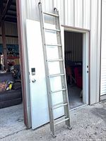 Full ladder leaning against doorway showing two sections and overall wear