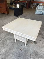 Overall view of square off-white distressed wood table closed