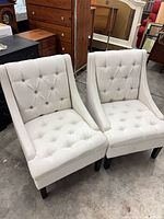 Front view of both cream tufted chairs showing overall design and legs