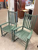 Two matching green wooden rocking chairs front view