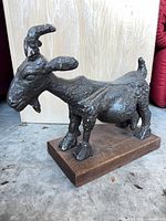 Front left view of cast metal goat on wood base