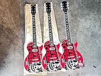 Three identical Red Man guitar signs laid side by side showing fronts