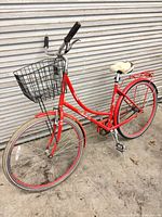 Full left side view of red step-through cruiser bicycle with basket