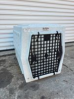 Front view of kennel with closed black grid door and RuffLand logo