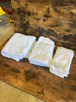Three folded stacks of white towels on wooden surface