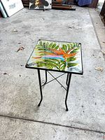 Full view of small metal table with decorative tile top