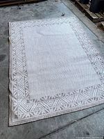 Full view of woven cream/beige area rug with geometric border