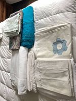 Stack of white, cream, turquoise and patterned linens including Frette and appliqué pieces