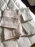 Folded pink striped duvet cover and pillowcase beside gray paisley set