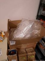 Open cardboard box containing loose, clear plastic sheeting or bags
