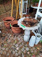 Concrete bird bath, two terracotta planters, two grey planters outdoors