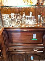 Bar cabinet shelf with decanters, stemware, wooden coasters visible