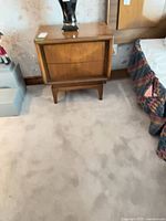 Nightstand beside bed showing overall design and tapered legs