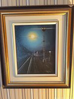 Framed night railroad painting on wall