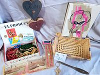Overview of lot showing cribbage board sleeve, wicker basket, wood hearts, cigar box with contents, letter opener and keychain