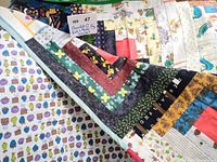 Overall view of quilt folded to show front patchwork and pear backing fabric, lot tag visible