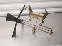 Side view of brass-tone dog whirligig showing propeller, frame and mounting sleeve