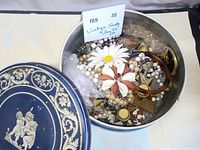 Tin opened showing mixed jewelry pieces