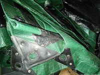 Folded green tarp showing reinforced corner with grommets