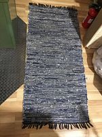 Blue tones woven cotton runner rug with fringe displayed on wooden floor