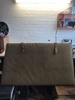 Front view of tan corduroy cushion hanging by two handles