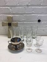 Group view of six beer glasses, tea cup with saucer, four etched liquor glasses, decorative cross