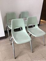 Four light green stackable chairs grouped